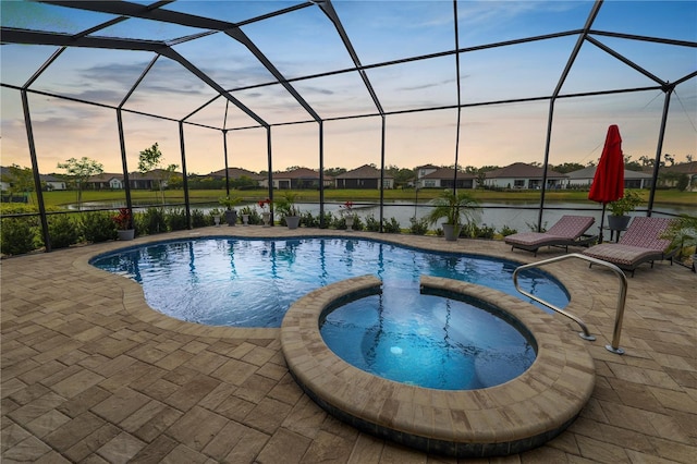 pool at dusk featuring an in ground hot tub, a water view, a lanai, and a patio area