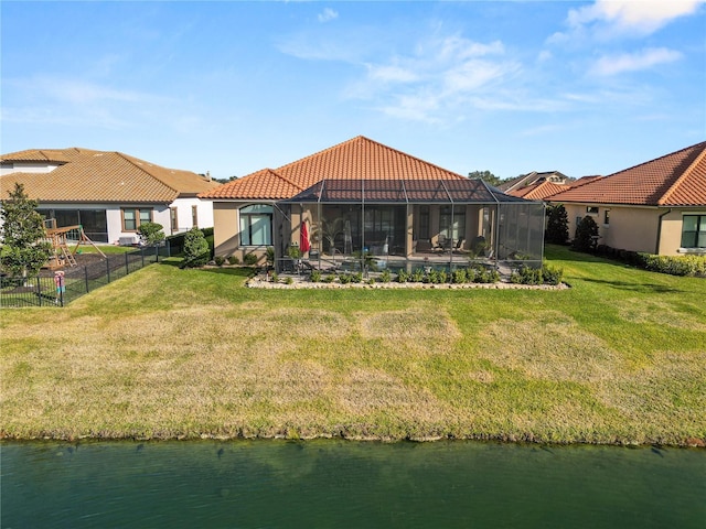 back of house with a water view, a yard, and glass enclosure