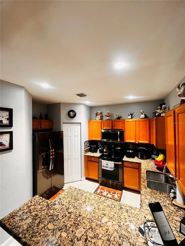 kitchen featuring sink, backsplash, light tile patterned floors, electric range, and black refrigerator with ice dispenser