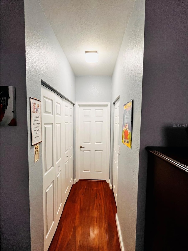 hallway featuring dark hardwood / wood-style flooring and a textured ceiling