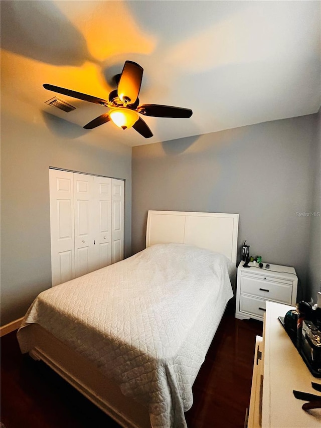 bedroom featuring dark hardwood / wood-style flooring, ceiling fan, and a closet