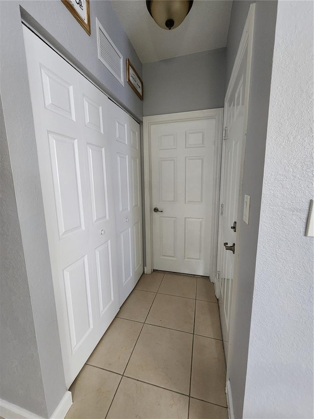 hallway featuring light tile patterned floors and visible vents