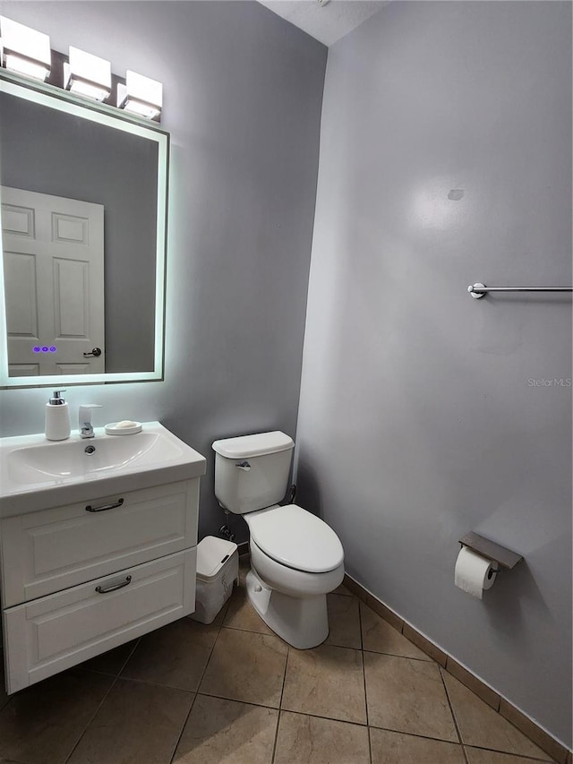 bathroom with toilet, tile patterned flooring, baseboards, and vanity