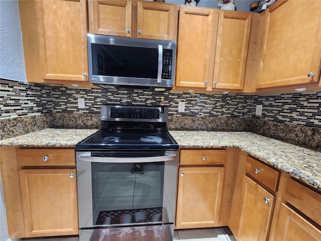 kitchen featuring light stone countertops, tasteful backsplash, stainless steel appliances, and brown cabinetry