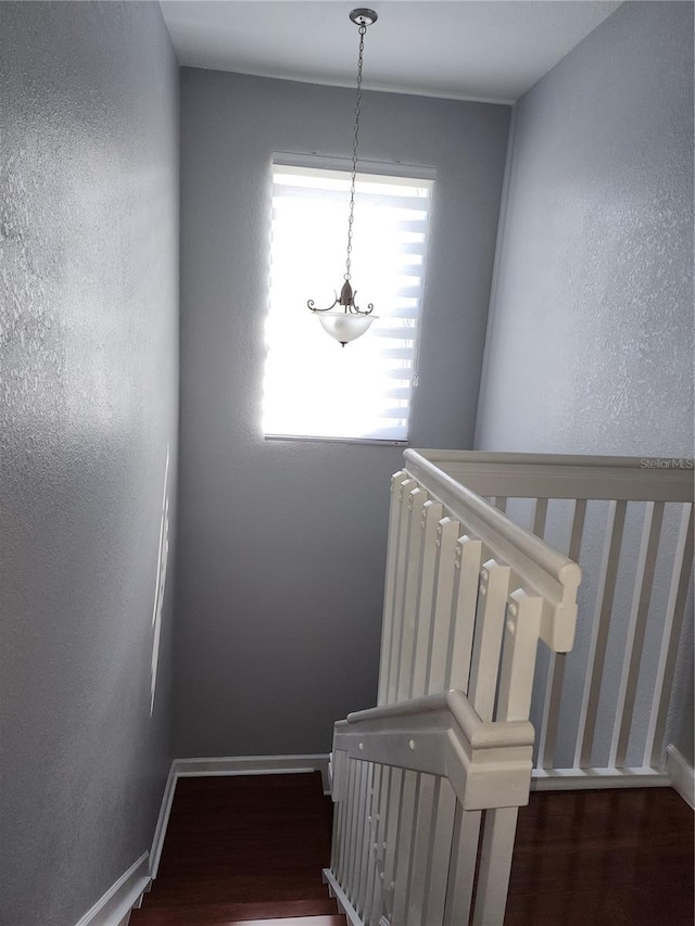 stairs featuring baseboards, wood finished floors, and a textured wall