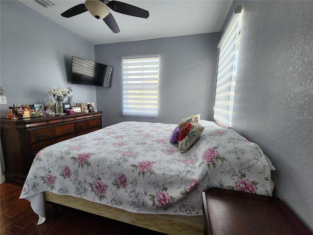 bedroom featuring dark wood-type flooring, visible vents, and a ceiling fan