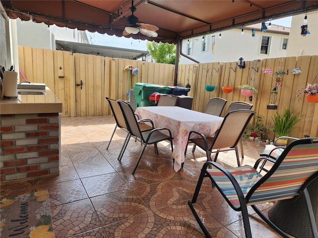 view of patio featuring ceiling fan, outdoor dining area, and fence