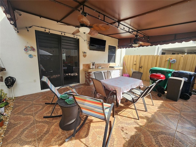 view of patio / terrace with a ceiling fan, outdoor dining area, and fence