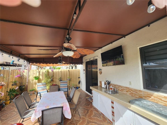 view of patio with outdoor dining space, a sink, and fence