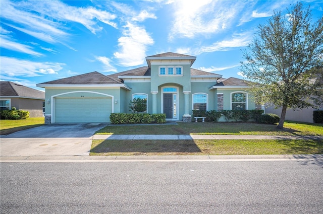 mediterranean / spanish-style house with an attached garage, driveway, a front lawn, and stucco siding