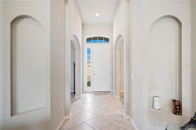 foyer featuring arched walkways and baseboards