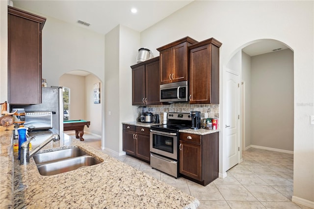 kitchen with visible vents, arched walkways, a sink, stainless steel appliances, and backsplash