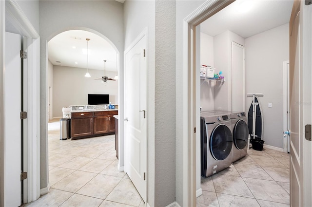 clothes washing area featuring arched walkways, laundry area, separate washer and dryer, and light tile patterned flooring