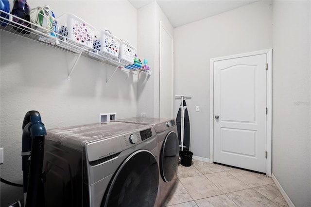 laundry area featuring washer and dryer, laundry area, baseboards, and light tile patterned floors