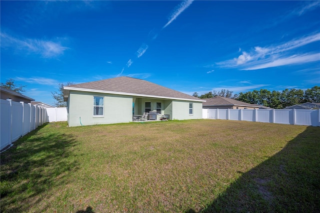 rear view of property with a yard, roof with shingles, a fenced backyard, and stucco siding