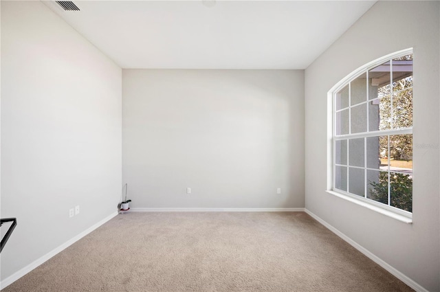 empty room with carpet flooring, visible vents, and baseboards