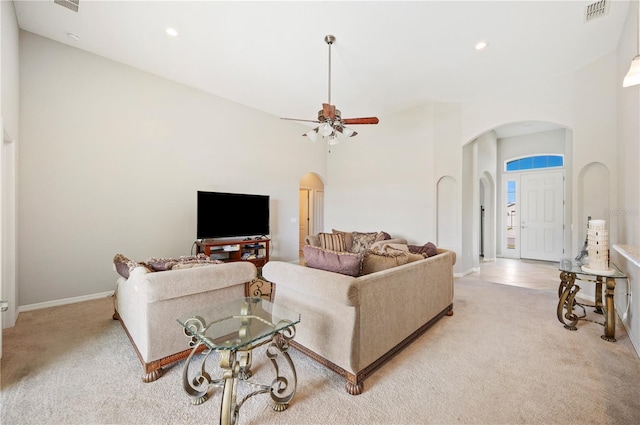 living room featuring light colored carpet, arched walkways, visible vents, and a high ceiling