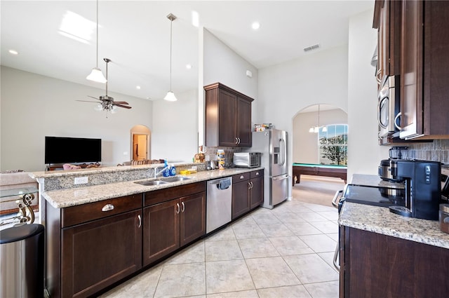 kitchen featuring dark brown cabinetry, arched walkways, stainless steel appliances, and a sink