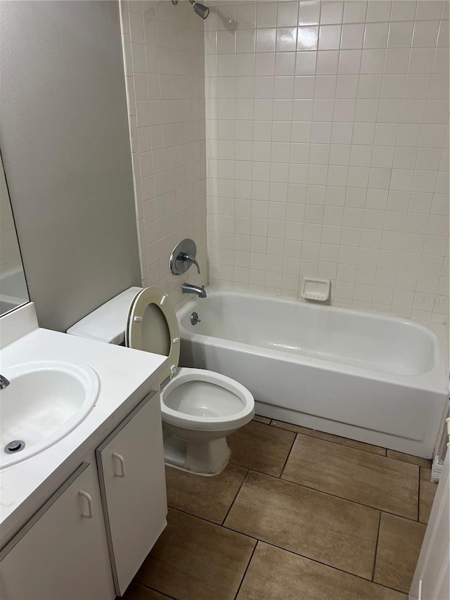 full bathroom featuring tiled shower / bath, vanity, and toilet