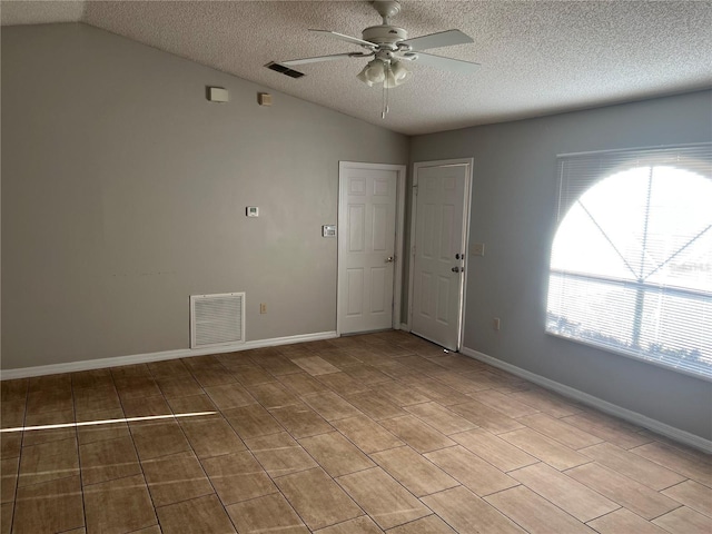 spare room featuring ceiling fan, lofted ceiling, a wealth of natural light, and a textured ceiling