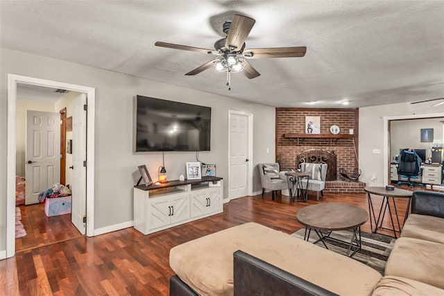 living room featuring ceiling fan, dark hardwood / wood-style floors, a fireplace, and a textured ceiling