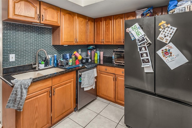 kitchen featuring appliances with stainless steel finishes, tasteful backsplash, sink, dark stone countertops, and light tile patterned floors