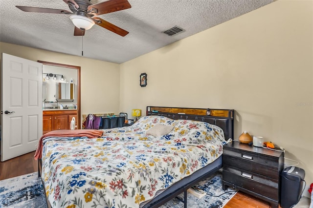 bedroom featuring connected bathroom, hardwood / wood-style floors, a textured ceiling, and ceiling fan