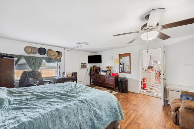 bedroom with a wall unit AC, light hardwood / wood-style floors, and ceiling fan