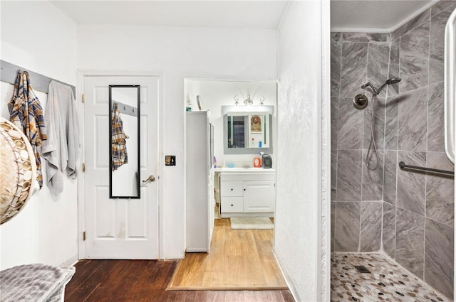 bathroom featuring a tile shower, vanity, and hardwood / wood-style flooring