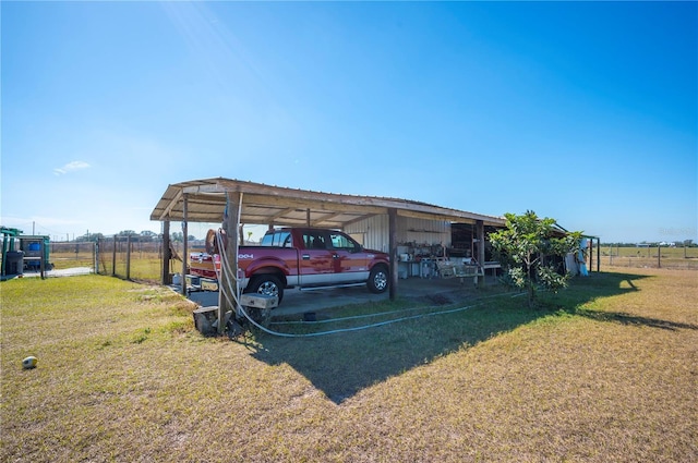 view of vehicle parking with a carport, a lawn, and a rural view