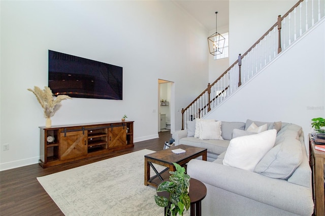 living room with a high ceiling, a notable chandelier, and dark hardwood / wood-style flooring