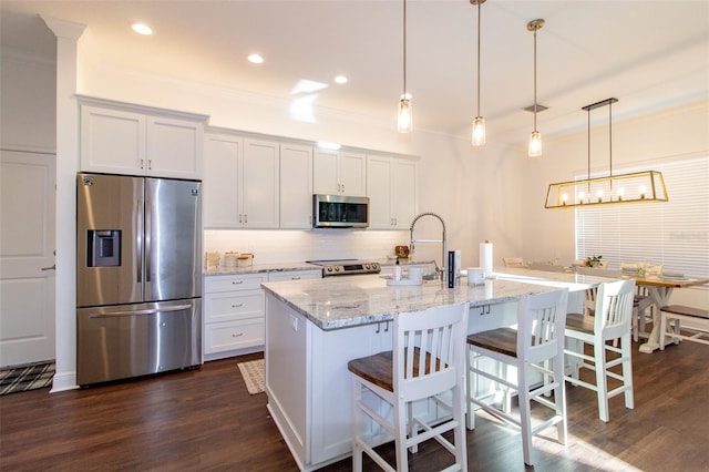 kitchen featuring hanging light fixtures, appliances with stainless steel finishes, a center island with sink, and white cabinets