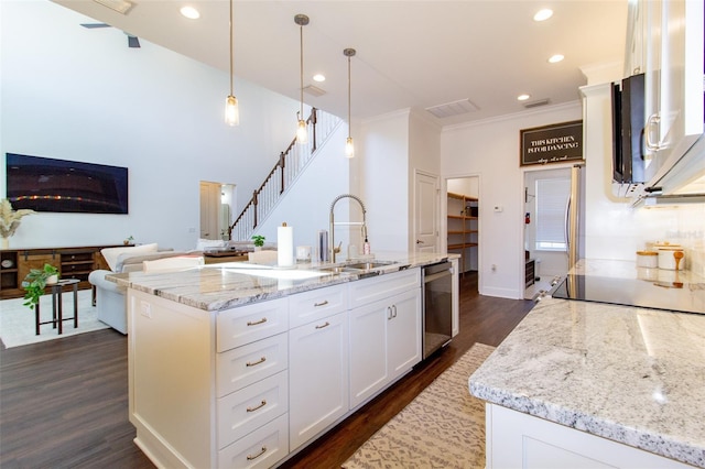 kitchen with sink, decorative light fixtures, an island with sink, and white cabinets