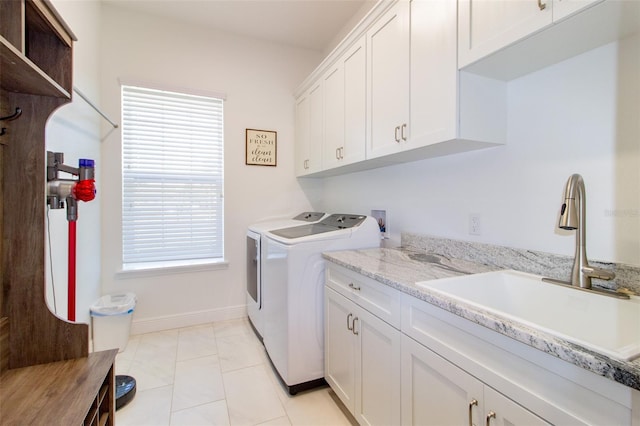 clothes washing area with cabinets, light tile patterned flooring, sink, and washing machine and clothes dryer