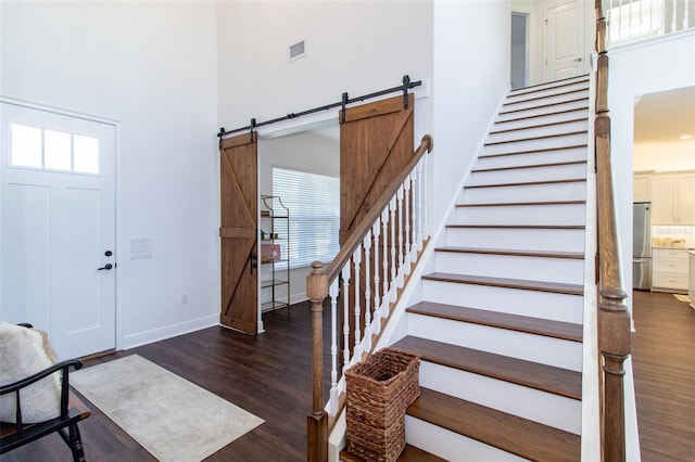 foyer entrance with dark wood-type flooring, a barn door, and a high ceiling