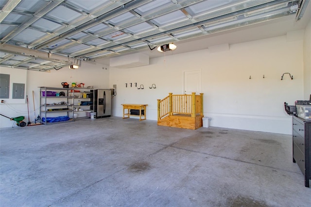 garage with stainless steel refrigerator with ice dispenser, a garage door opener, and electric panel