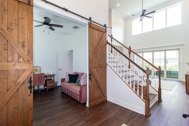 stairs with hardwood / wood-style floors, a wealth of natural light, a barn door, and ceiling fan