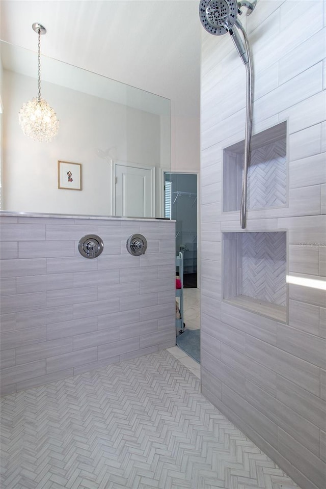 bathroom featuring tiled shower and an inviting chandelier