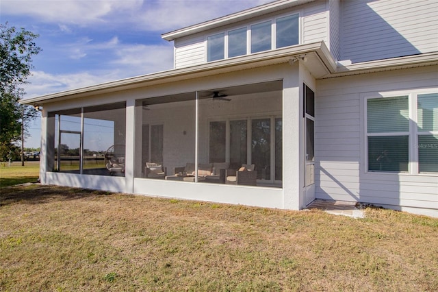 rear view of property featuring ceiling fan, a sunroom, and a lawn