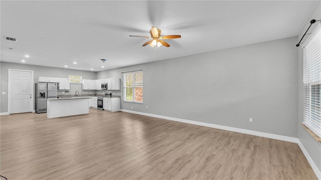 unfurnished living room featuring sink, light hardwood / wood-style floors, and ceiling fan