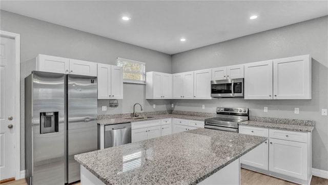 kitchen with sink, a kitchen island, white cabinets, and appliances with stainless steel finishes