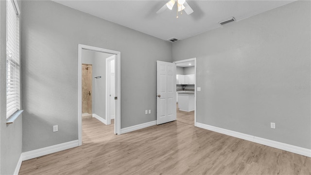 unfurnished bedroom featuring light wood-type flooring, connected bathroom, and ceiling fan