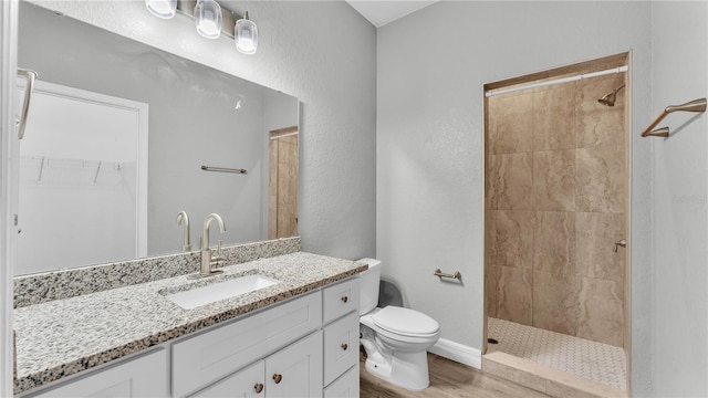 bathroom with vanity, wood-type flooring, toilet, and tiled shower