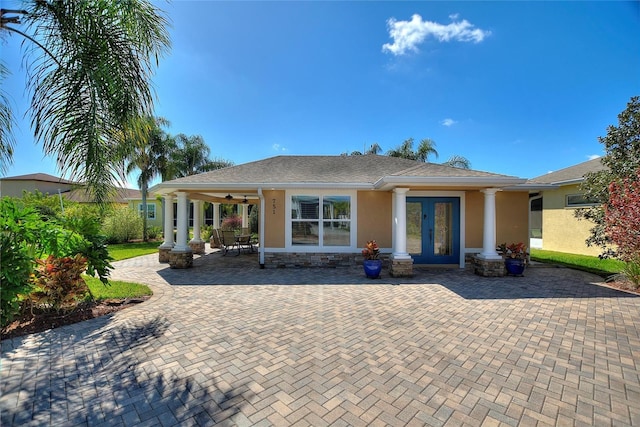 back of property with stucco siding, a patio area, stone siding, and french doors