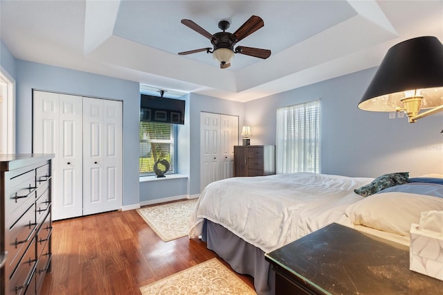 751 Meandering Way, Polk City, FL 33868 - bedroom with a tray ceiling, two closets, a ceiling fan, wood finished floors, and baseboards
