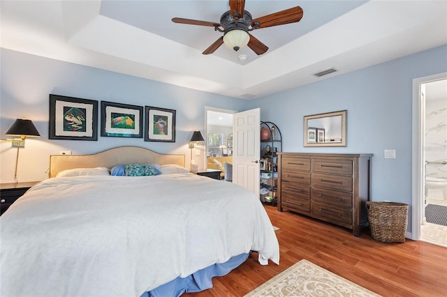 751 Meandering Way, Polk City, FL 33868 - bedroom with ensuite bathroom, light wood-style flooring, visible vents, a ceiling fan, and a raised ceiling