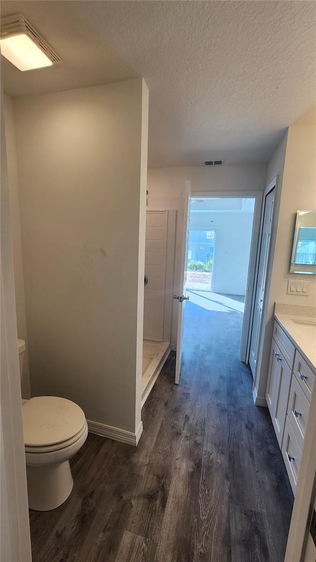 bathroom with walk in shower, toilet, a textured ceiling, vanity, and hardwood / wood-style flooring