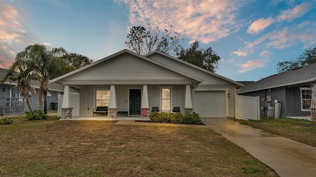 view of front facade with board and batten siding, concrete driveway, a front yard, covered porch, and a garage