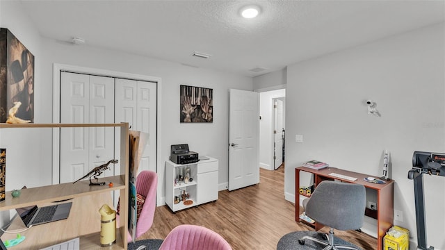 office featuring visible vents, a textured ceiling, baseboards, and wood finished floors