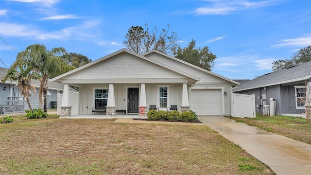 view of front of house with a front yard, covered porch, concrete driveway, a garage, and board and batten siding